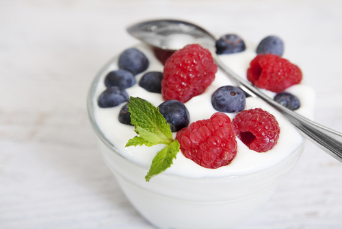 plain yogurt with blueberries and raspberries on top, in a glass
