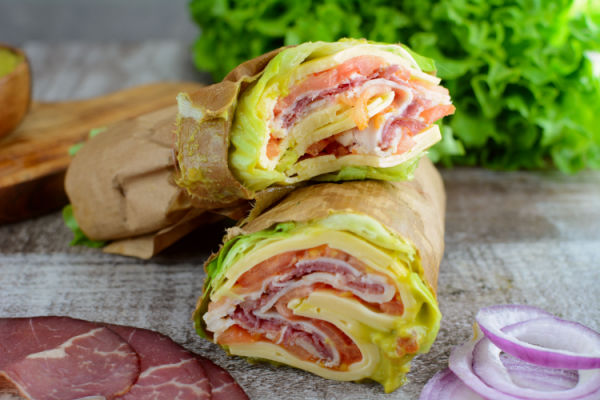 A close-up view of a lettuce wrap with bacon and cheese.