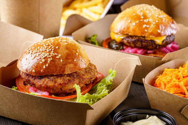A table view of three burgers on sesame seed buns.