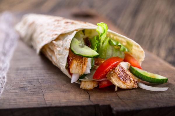 A close-up view of a chicken wrap on a tortilla.
