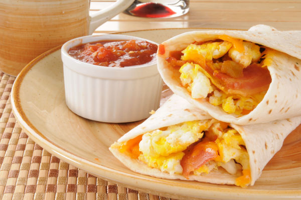 A close-up view of a burrito filled with bacon, cheese, and egg.
