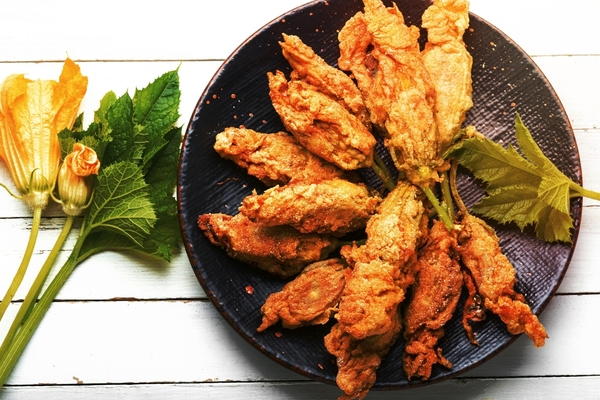Crispy baked zucchini fries on a plate with zucchini flowers