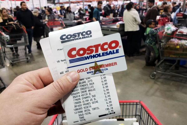 A photo of a person's hand holding a Costco Wholesale receipt with the company name and logo clearly visible.