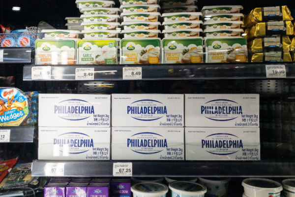 A photo of a grocery store display featuring various types of cream cheese in refrigerated cases.