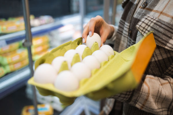 A photo of a grocery store display featuring different types of eggs, such as white, brown, and organic eggs, arranged neatly in cartons.