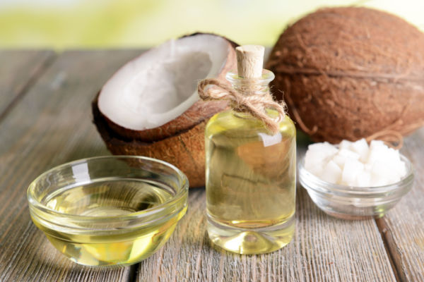 A photo of a coconut and a jar of coconut oil, arranged side by side.