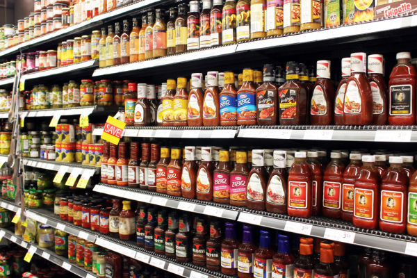 A photo of a grocery store display featuring a variety of condiments, such as ketchup, mustard, mayonnaise, hot sauce, and salad dressings.
