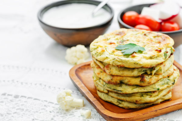 A stack of small cauliflower tortillas on a white plate.