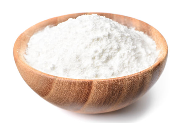 An isolated wooden bowl filled with Stevia powder, a natural sweetener derived from the Stevia plant.