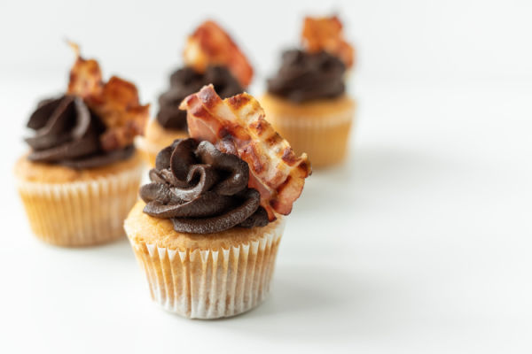 Close-up of a decadent cupcake with a unique twist: bacon-infused, savory-sweet frosting, adding a delightful balance of saltiness and richness.