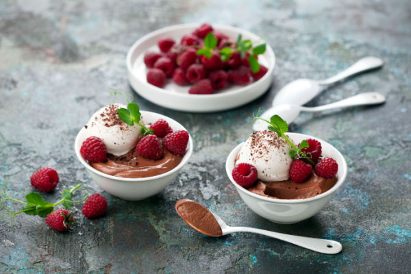 Keto chocolate mousse crowned with a dollop of whipped cream and garnished with a plump, juicy strawberry.