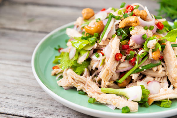A plate of chicken salad with peppers, onions, and scallions