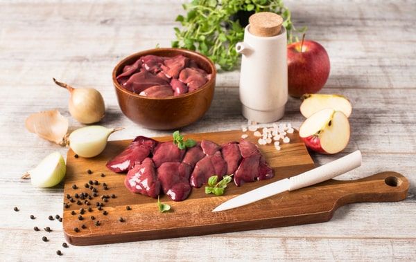Raw chicken liver on a wooden board with ingredients