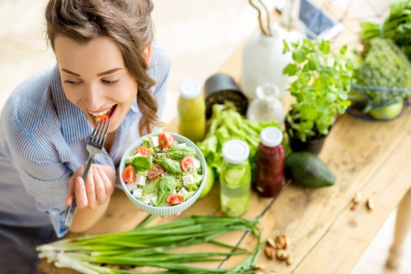 The 10 Day Detox: Say Goodbye to Toxins and Hello to Energy 4 A woman eating a salad served in a while bowl