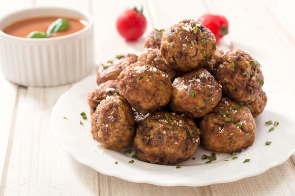 A stack of meatballs on a plate with herbs and spices