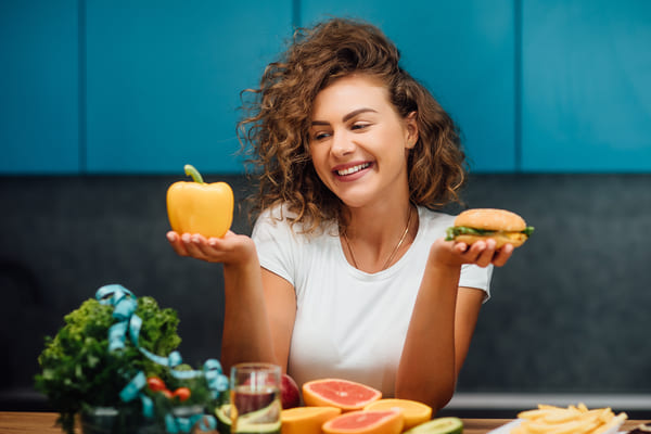 Zaxbys Low Carb: Unveiling the Best Kept Secret 3 A joyful woman holding a pepper and a burger, radiating happiness and satisfaction.