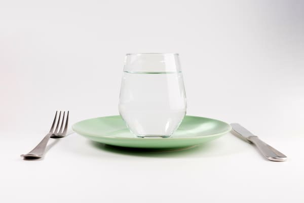 A glass of water on top of an empty plate