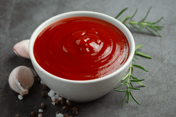 A bowl filled with ketchup, a popular condiment known for its tangy and savory flavor.