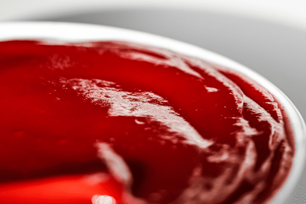 A close-up view of ketchup in a bowl, showcasing its smooth texture and vibrant red color.