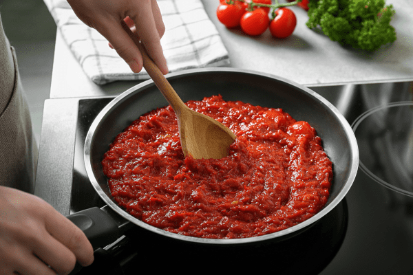 A photo of homemade tomato sauce being cooked in a pot, capturing the process of simmering fresh tomatoes and other ingredients.