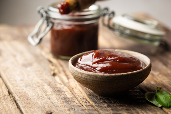 BBQ sauce in a saucer and a jar with basting brush