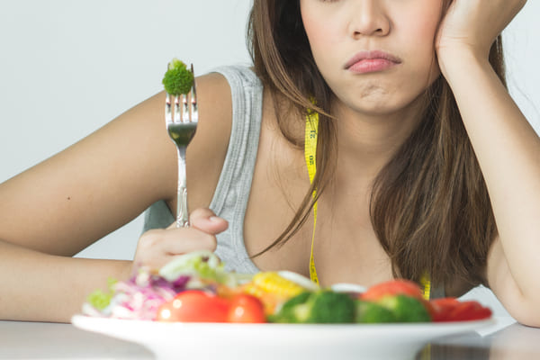A photo of someone contemplating in front of a plate of vegetables.