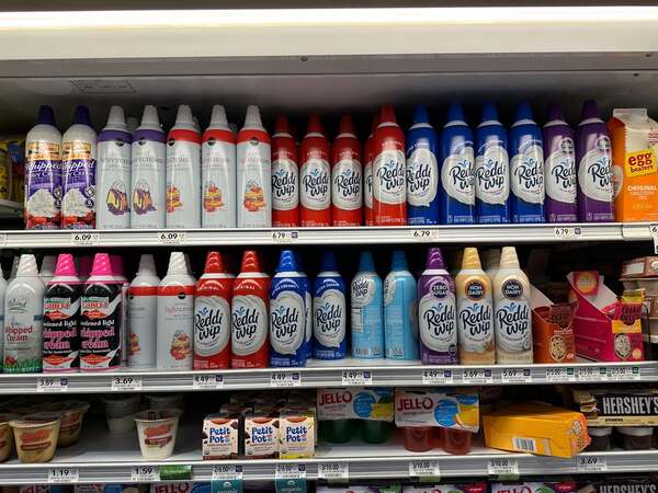An aisle of whipped cream at the grocery