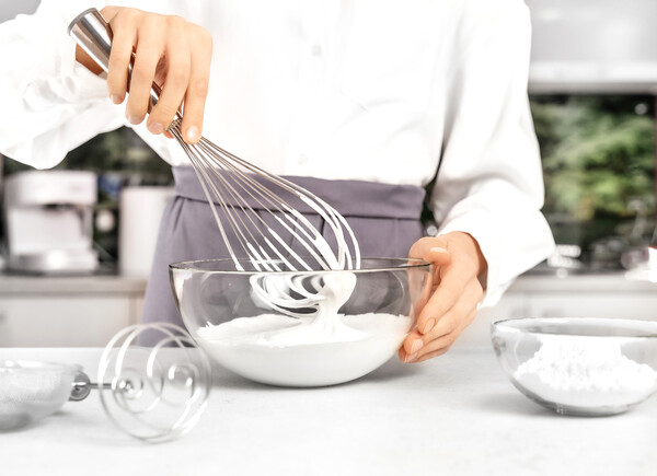 A woman whisking heavy cream in a bowl