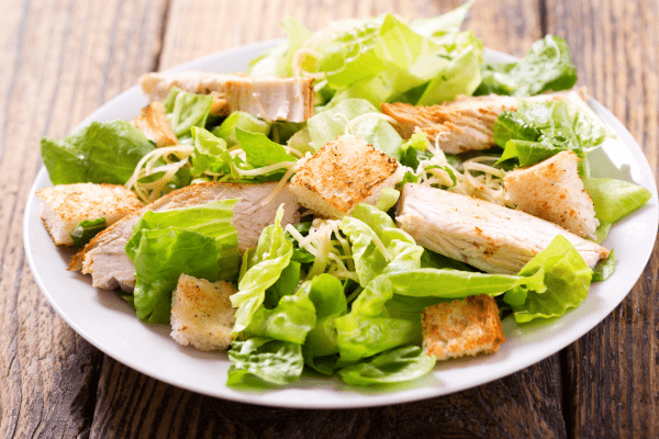 A plate featuring a Caesar salad, showcasing crisp lettuce, grated Parmesan, croutons, and Caesar dressing