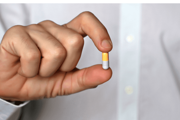 Is the One Shot Keto Diet Safe and Effective? Unraveling the Facts 4 Pill held between two fingers, representing medication intake or health management