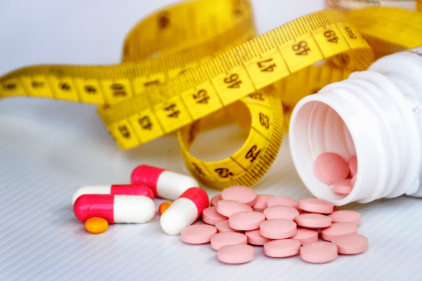Is the One Shot Keto Diet Safe and Effective? Unraveling the Facts 5 Scattered pills with a tape measure nearby.