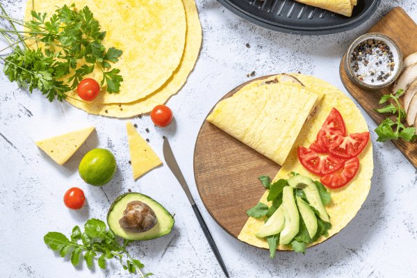 A photo of a corn tortilla topped with fresh avocado slices, juicy tomatoes, and other delicious ingredients, creating a delightful and colorful meal.
