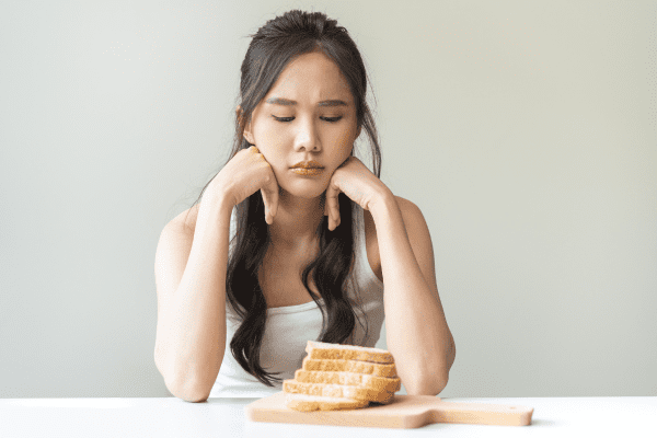 A photo of a woman looking at breads with a sense of struggle, as she experiences hungry on keto.