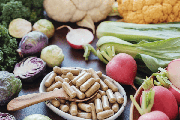 Is the One Shot Keto Diet Safe and Effective? Unraveling the Facts 7 Bowl containing pills alongside a selection of fresh vegetables, suggesting a combination of medication and nutritious elements.
