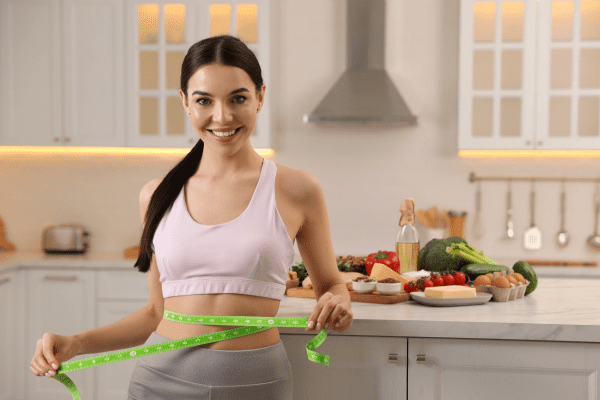 A woman measuring her waist during ketosis for progress tracking.