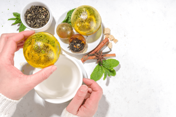 A woman holding a tea bomb, ready to place it into a cup for brewing.