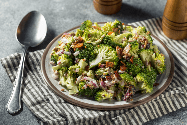 A plateful of delicious broccoli salad, featuring a delightful mix of broccoli florets, crisp onions, and crunchy nuts, creating a satisfying combination of flavors and textures.