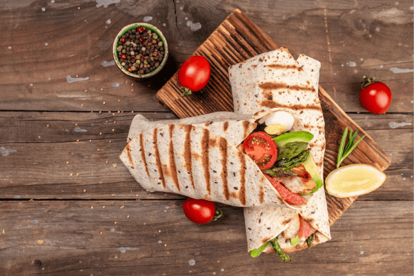 A delicious burrito filled with avocado, tomatoes, and various other ingredients.