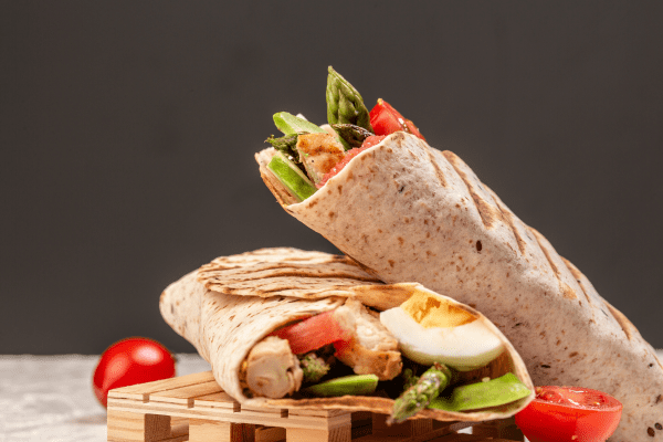 A delicious burrito filled with avocado, tomatoes, and various other ingredients.