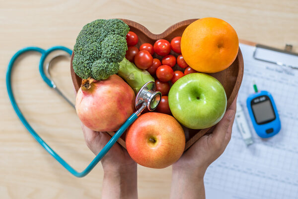 Fruits and vegetables in a heart-shaped dish and a blood sugar monitor