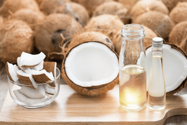 Are Keto Coconut Clusters a Healthy Snack Choice? 6 A whole coconut, with its meat exposed, accompanied by a bottle of MCT (Medium-Chain Triglyceride) oil, highlighting the natural source of MCTs in coconuts.