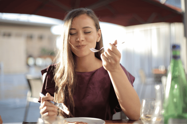 Are Keto Coconut Clusters a Healthy Snack Choice? 7 A joyful woman enjoying her meal with a bright and content expression.