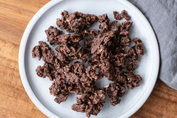 Are Keto Coconut Clusters a Healthy Snack Choice? 4 A top view of delectable coconut clusters nestled on a plate, generously coated in rich, velvety chocolate, creating a delightful and indulgent treat.