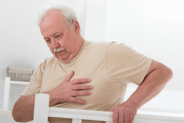A man holding her chest, appearing to experience heart palpitations while following a keto diet.