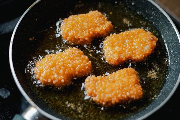 Frying chicken nuggets in oil in a pan