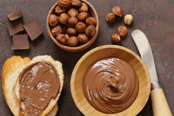 Sugar Free Nutella: Satisfy Your Sweet Tooth Guilt Free 7 A bowl of chocolate and hazelnut spread accompanied by bread generously coated with the spread.