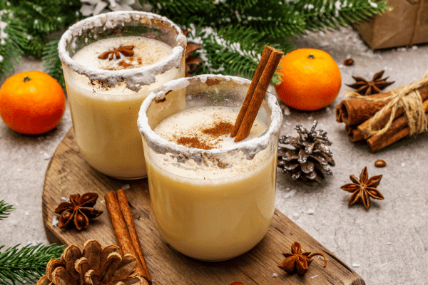 Keto Eggnog 101: A Complete Recipe Guide for the Holidays 2 Two glasses of festive eggnog, garnished with a sprinkle of cinnamon, set in a cozy Christmas arrangement, capturing the holiday spirit with warm and spiced flavors.