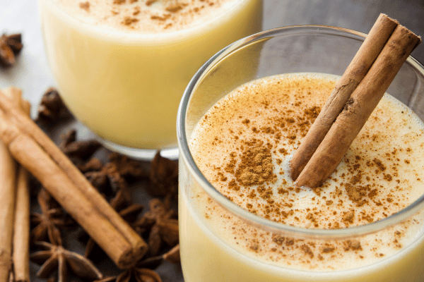 Keto Eggnog 101: A Complete Recipe Guide for the Holidays 3 A close-up photo of a glass filled with cinnamon eggnog showcases this festive holiday drink's rich texture and inviting spiced aroma.