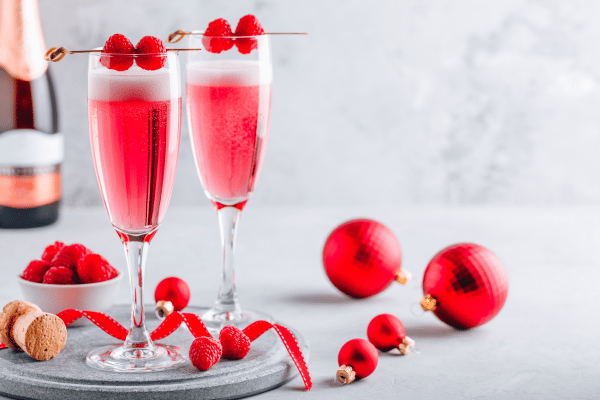 Pink Whitney Carbs: A champagne-like cocktail in a lovely pink hue, adorned with assorted berries for a visually appealing and flavorful drink.