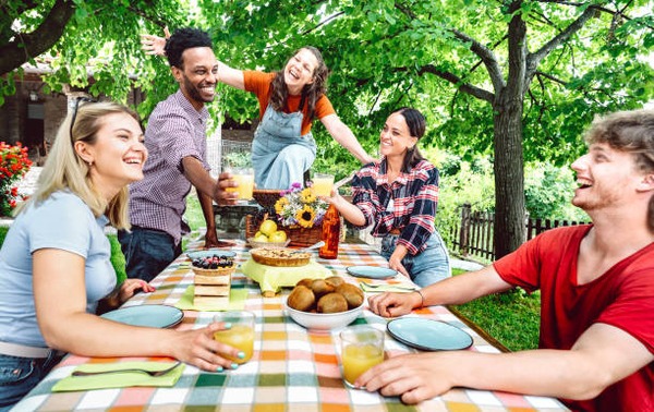 Keto Cook Out Delights: Irresistible Recipes for Your Feast 2 A group of friends talking and laughing on a picnic table with food and drinks